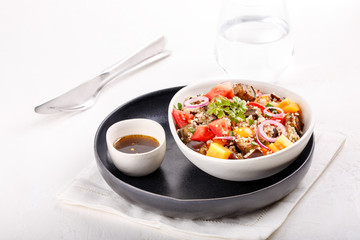 Quinoa salad with roasted eggplant, fresh tomatoes and red onion.   Vegan or vegetarian food. Healthy salad in bowl served on white table.