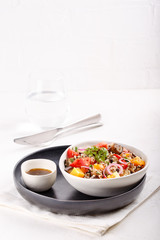 Quinoa salad with roasted eggplant, fresh tomatoes and red onion.   Vegan or vegetarian food. Healthy salad in bowl served on white table.