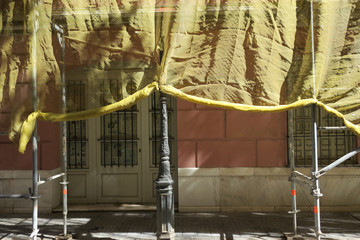undercover, facade of a building covered with scaffolds an yellow fabric in Malaga