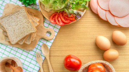 Homemade sandwich breakfast preparing. Whole wheat bread stacked on a wooden cutting board. Slice tomatoes and lettuce placed on a wooden plate. Food concept. Cooking ingredient.