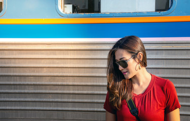 Portrait of beautiful  traveler Asian woman wearing sunglasses with train background