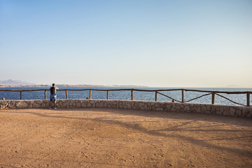 Traveling man with backpack looks on sea and sky