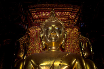 Fototapeta premium closeup gold buddha statue in thai lanna temple with soft-focus and over light in the background, Chiang Rai Province, Thailand