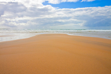 Fototapeta na wymiar Irish beach with sand and cloudy sky (Ireland)