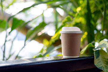 closeup paper cup of hot coffee with soft-focus and over light in the background