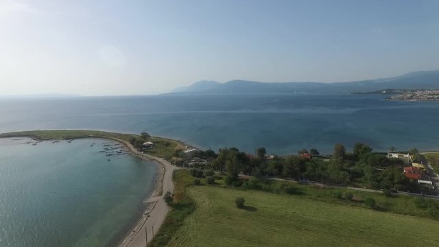 Aerial shot at Greek sea with dji fantom 3. Beautiful small port for fishing boats. Sea around trees. Blue sky. Country road in Greece. End of the road.