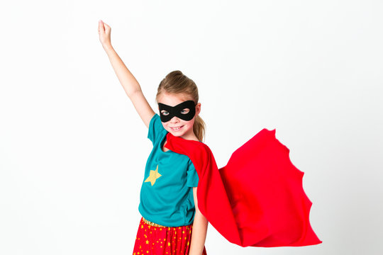 blond supergirl with black mask and red cape posing in front of white background