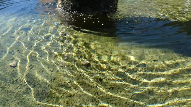 Nice detail of the reflections and waves of water from a stone fountain with water splashing