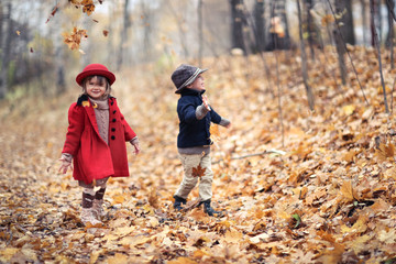 Children walk in autumn forest, kick leaves,