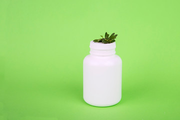 White bottle on a green background. bottle and leaves. Massage and leaves. Shampoo and shower gel. Natural cosmetic product. organic green leaves. Essential oil with herbal extract