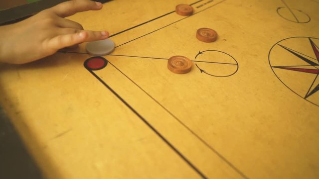 close up at child playing carom slow motion, carrom board, indian traditional games