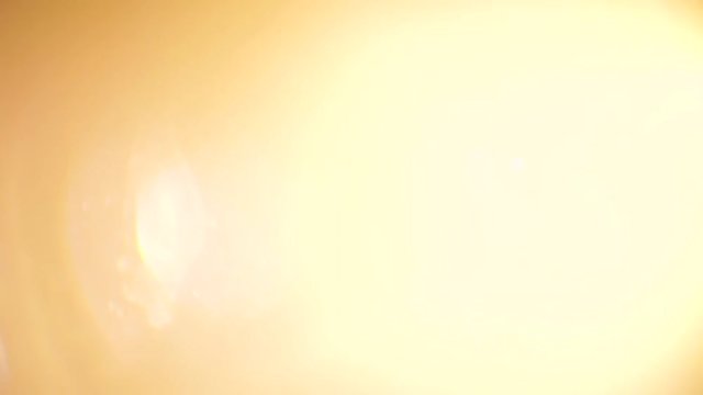 Golden light flares shining bright over a dark background. Abstract light in motion for transition purposes.