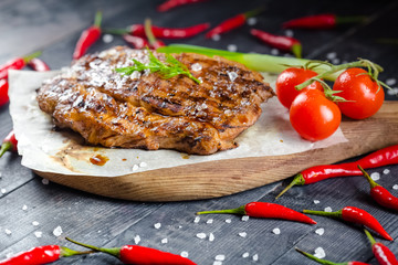 grilled kebab grilled meat steak lies on a wooden vintage old board rustic, chili, with tomatoes,...