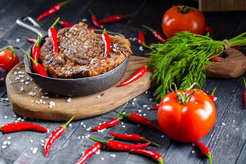 grilled kebab grilled meat steak lies in an iron frying pan, on a wooden vintage old board rustic,...