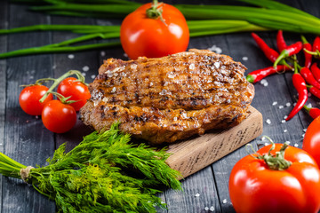 grilled kebab grilled meat steak lies on a wooden vintage old board rustic, chili, with tomatoes,...