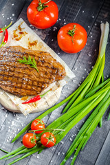 grilled kebab grilled meat steak lies on a wooden vintage old board rustic, chili, with tomatoes,...