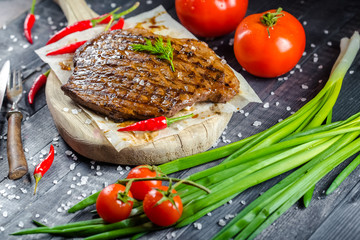 grilled kebab grilled meat steak lies on a wooden vintage old board rustic, chili, with tomatoes,...