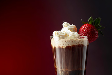 Chocolate drink with whipped cream and strawberry on a dark background.