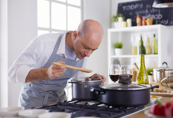 Handsome man is cooking on kitchen and smiling