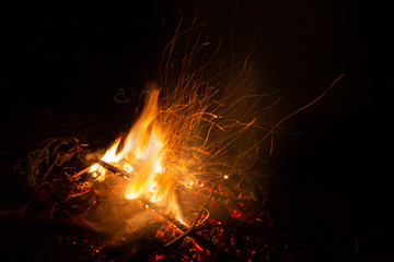 Fototapeta na wymiar Bonfire in the night. Beautiful orange sparkles on a black background.