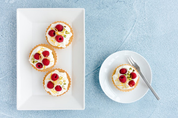 Raspberry Tartlets on Plates and Blue Concrete Background
