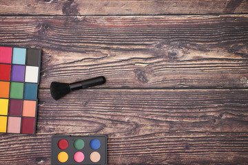 Eye shadow palettes and make up brush on the wooden table 