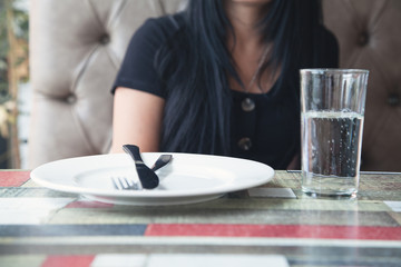 Obraz na płótnie Canvas Woman in restaurant. Fork and a knife on empty white plate