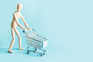 Buyer as dolls with grocery trolley on blue with space for text. Concept shopping.
