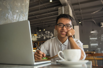 Asian freelancer smiling and working in the cafe