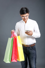 Indian man with shopping bags and showing mobile screen 