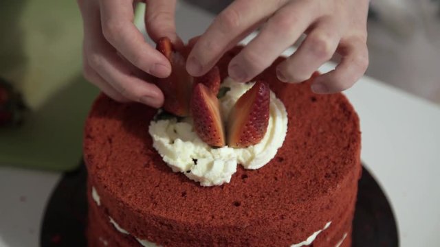 Making red velvet cake at home. Decoration of the cake with strawberries and cream. Corrects strawberries