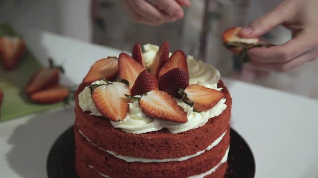 Making red velvet cake at home. Decoration of the cake with strawberries and cream.