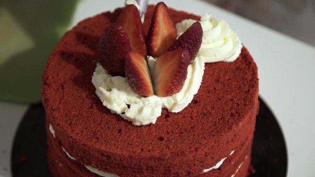 Making red velvet cake at home. Decoration of the cake with strawberries and cream. Moving back and forth