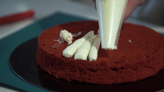 Making red velvet cake at home. Smearing a layer of cake cream around the circumference. Close up. Fail