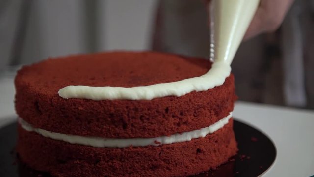 Making red velvet cake at home. Smearing a layer of cake cream around the circumference. Close up. Static plan
