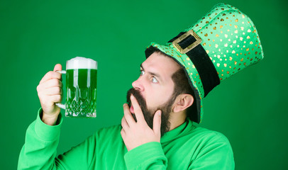 Irish you were beer. Hipster in green leprechaun hat holding beer mug. Bearded man toasting to...