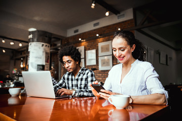 Multiethnic business team meeting at cafe, working using laptop and smartphone