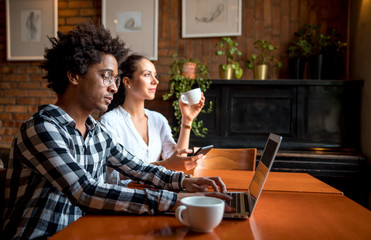 Multiethnic business team meeting at cafe, working using laptop and smartphone