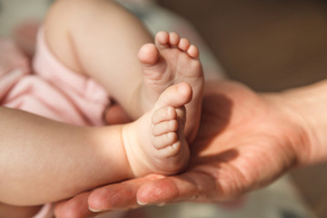 Closeup photo of a tiny baby feet in father hand