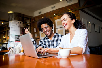 Multiethnic business team meeting at cafe, working using laptop