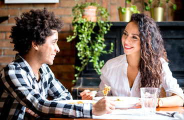 Happy young couple eating lunch together at restaurant, african american people having fun