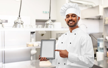 cooking, technology and people concept - happy male indian chef in toque with tablet computer over restaurant kitchen background
