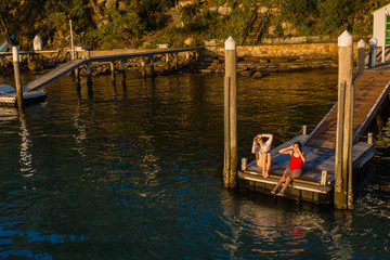 Obraz premium two young woman sitting on a jetty in the afternoon light