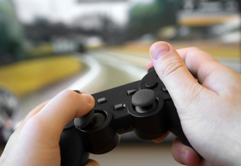 Man playing racing video game on TV. Gamepad controller in hands.