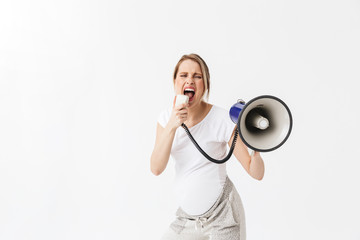 Screaming beautiful young pregnant woman posing isolated over white wall background holding loudspeaker.