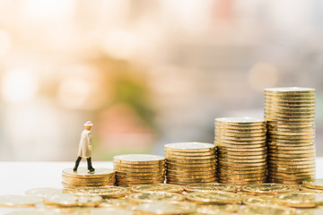 Miniature people: Small figure standing on stack of coin. Money and financial concepts.