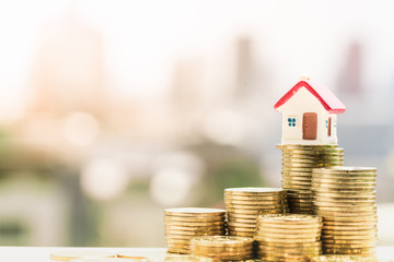 Concept for property ladder, mortgage and real estate investment. House models on top of coins pile...