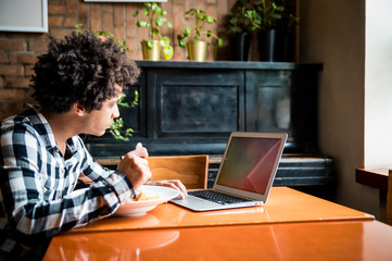 Empty blank screen of laptop on table in restaurant, young man using computer while eating
