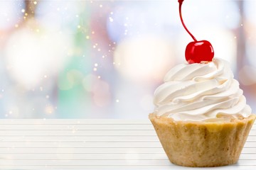 Cupcake with whipped cream and cherry isolated on background