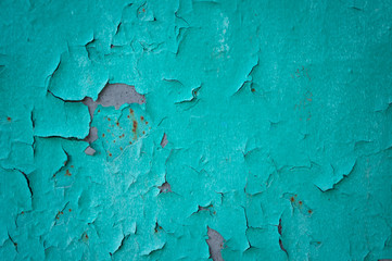 Old turquoise wall with cracks and the exfoliated paint